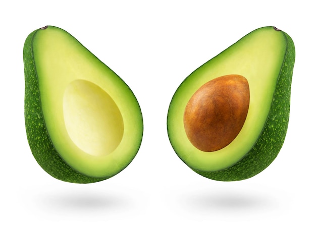 Foto due metà di un avocado verde e il nucleo del frutto levitano su uno sfondo bianco