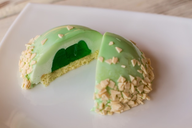 Two halves of green dessert. Glazed cake with green filling. Mint mousse cake on plate. Sweet snack for a guest.