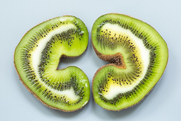 Two halves of a heart-shaped ugly kiwi in a section on a gray surface.