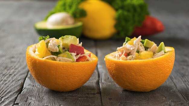 The two halves of the oranges with chicken salad and avocado. Diet food of tropical fruits and chicken.