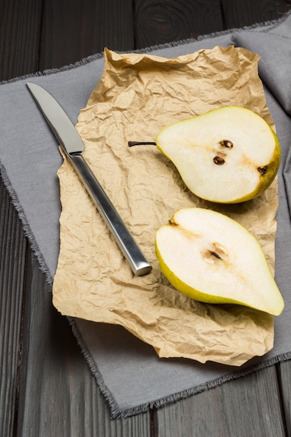 Photo two halves of pear on gray napkin. kitchen knife. top view.