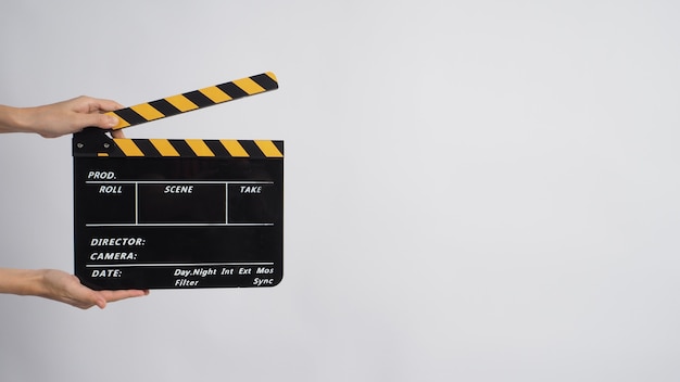 Two Hand's holding black with yellow Clapper board on white background.
