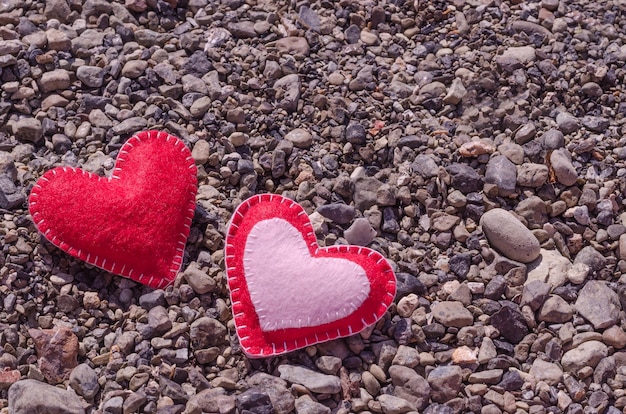 Due cuori fatti a mano su una spiaggia estiva con ciottoli con spazio di copia