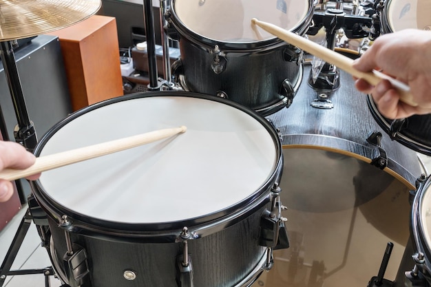 Two hands drumsticks beating on a drum, first-person view