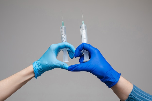 Two hands in gloves holding syringes space