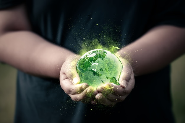 Photo two hands hold the green globe and the magic light. concept of saving the world and earth day