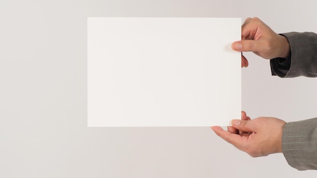 Photo two hands holding blank board white paper and wearing a grey suit on white background.  space for text.