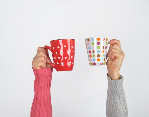 Two hands holding ceramic mugs