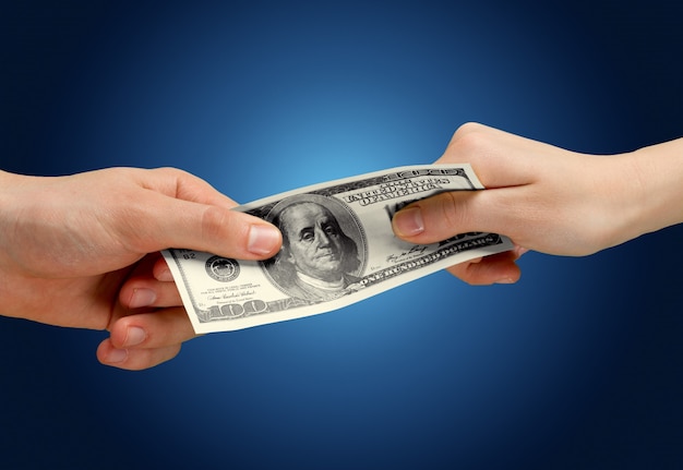 Two hands holding one hundred dollars banknote over blue background