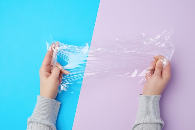 Two hands holding a piece of transparent plastic film