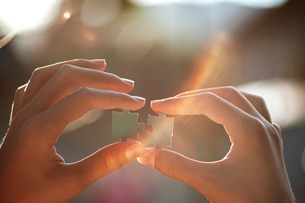 two hands holding puzzle pieces on a bokeh background