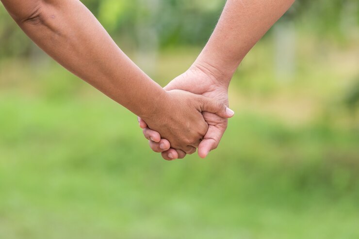 Photo two hands holding together. help or support concept. on green blur background