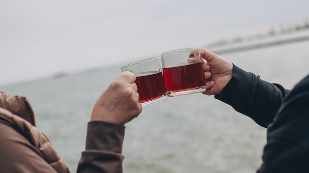 two hands holding transparent cups of tea