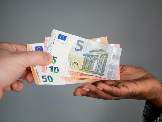 Two hands paying euro note