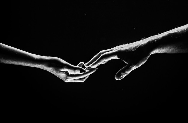 Photo two hands stretch each other black background couple in love holding hads close up helping hand