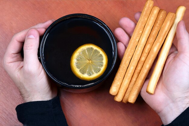 一杯のお茶とビスケットの両手がクローズアップ