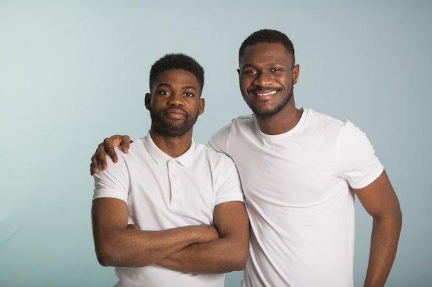 Due bei uomini africani in magliette bianche su sfondo blu