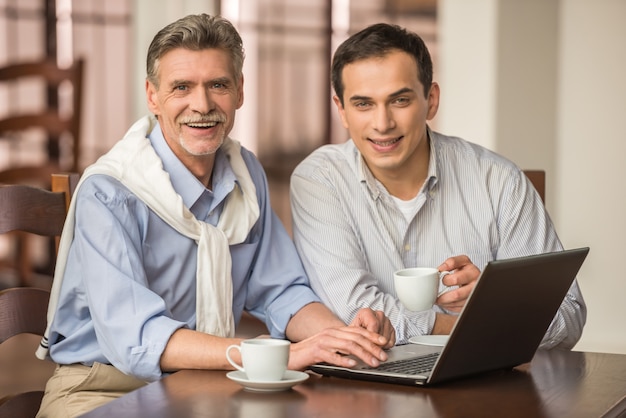 Two handsome businessmen are using laptop.