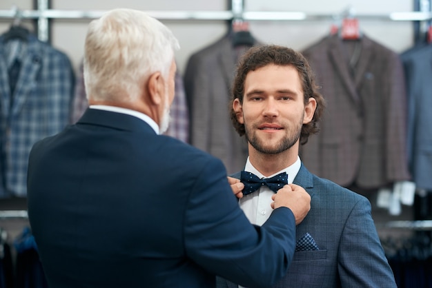 Two handsome men choosing bow tie in store.