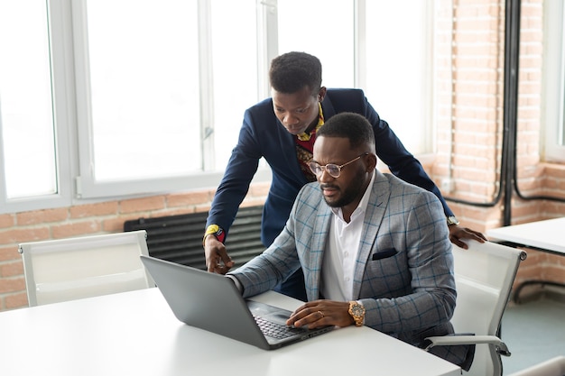 two handsome young african men at the table with laptop