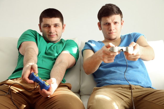 Photo two handsome young men playing video games in room