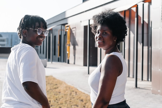 Two happy African-American women are walking down the street in the summer.