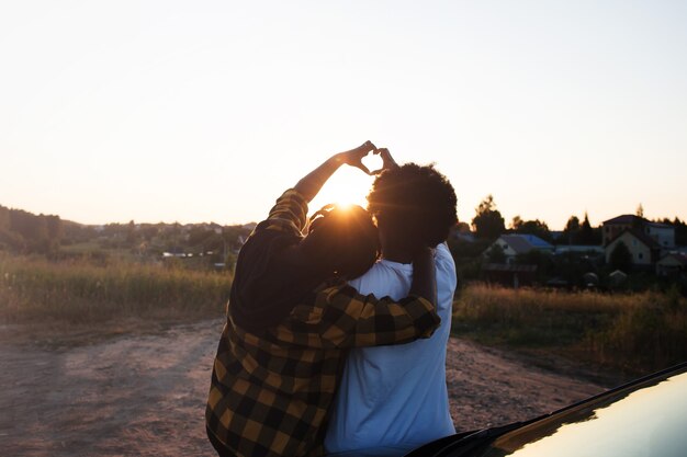 Two happy African-American women near the car look at the sunset, lifestyle