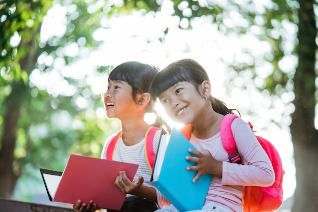 2人の幸せなアジアの学生の友人が公園で勉強を楽しんでいます