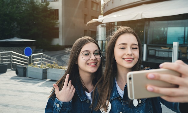 Two happy best friends streaming live video on city street