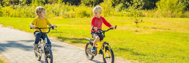 Two happy boys cycling in the park banner long format