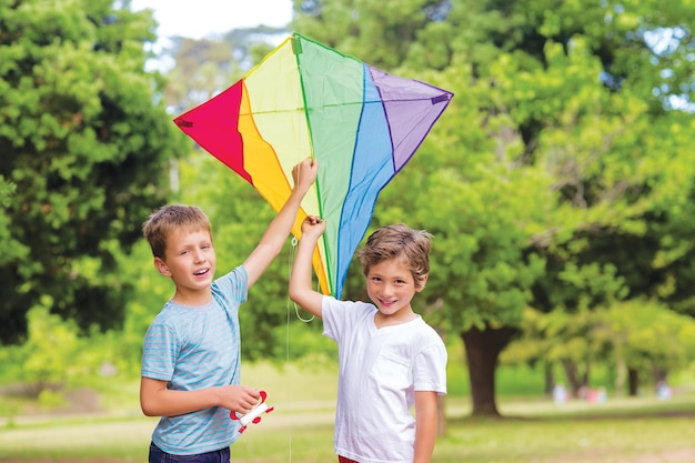 Two happy boys holding a kite in the park