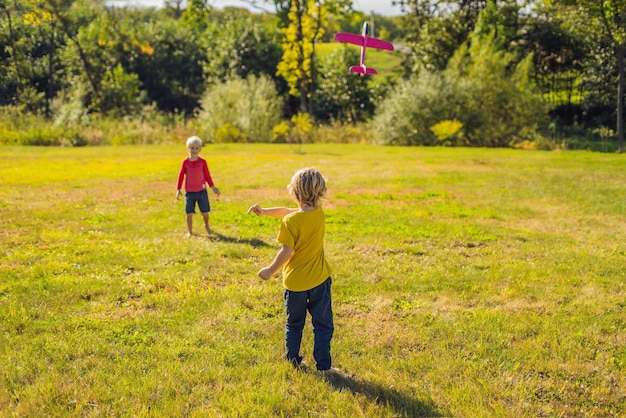 Two happy boys playing with toy plane in the park.