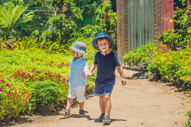 Two happy brothers running together on a park path in a tropical park