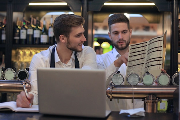 Due gestori felici del caffè che lavorano al computer portatile.