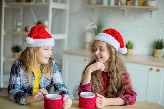 Two happy caucasian girls in red hats in the kitchen