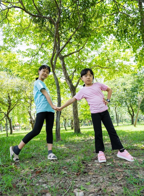 公園の屋外で笑顔で2人の幸せな子供の女の子緑の公園で夏の日を遊んで楽しんでいる子供たち