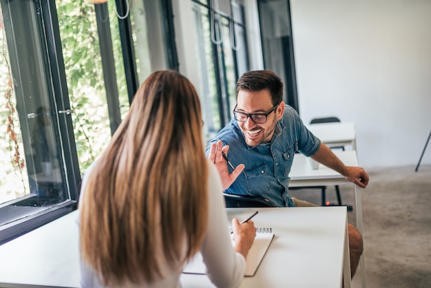 Two happy college students talking in classroom.