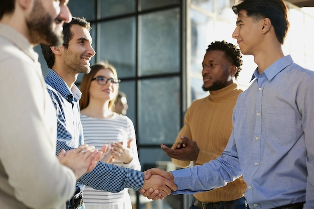 Two happy diverse professional business men executive leaders shaking hands at office meeting