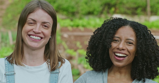 Foto due donne felici e diverse in piedi all'aperto nel campo verde ridendo e sorridendo volti ritratto di persone gioiose nella campagna agricola