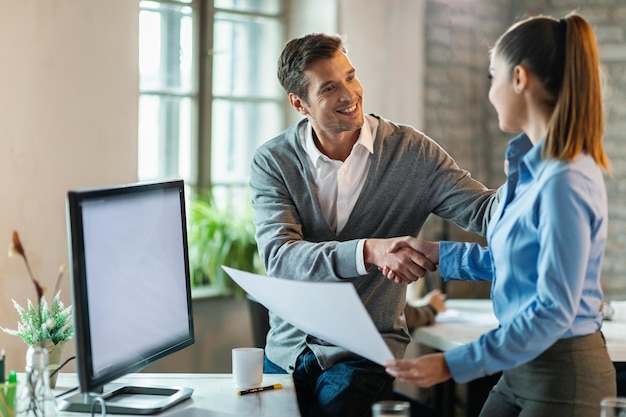 Photo two happy entrepreneurs shaking hands after making an agreement in the office focus is on man