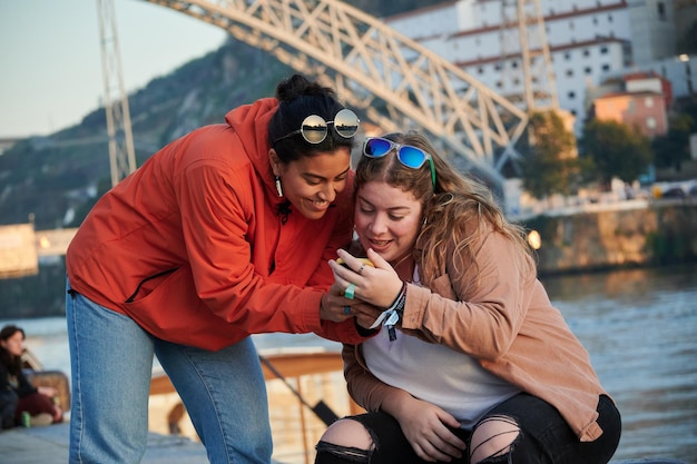 Two happy female friends watching the phone of one of them