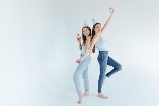 Two happy friends celebrating birthday in party hats