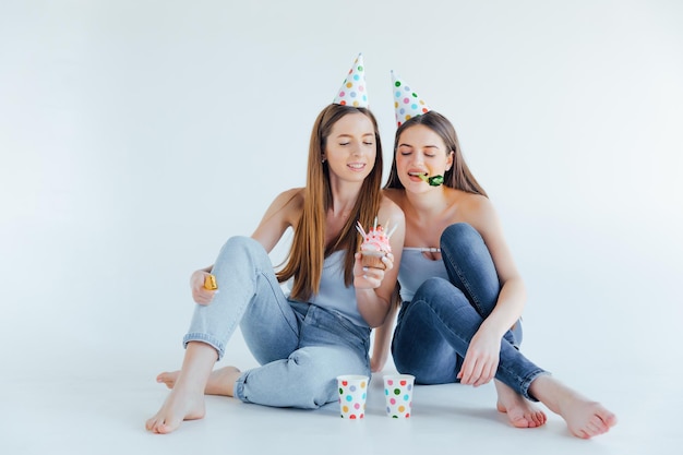 Two happy friends celebrating birthday in party hats