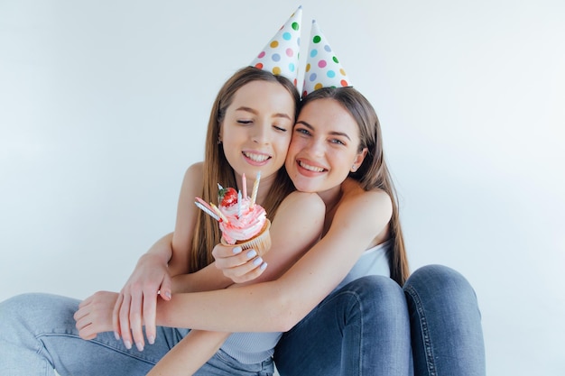Two happy friends celebrating birthday in party hats