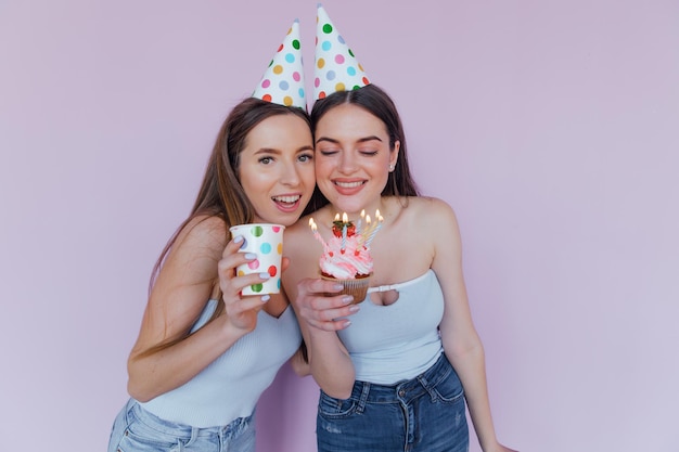 Two happy friends celebrating birthday in party hats