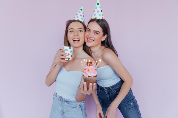 Two happy friends celebrating birthday in party hats
