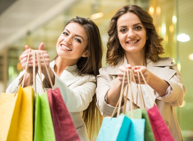 Two happy friends is shopping in mall and looking at camera.