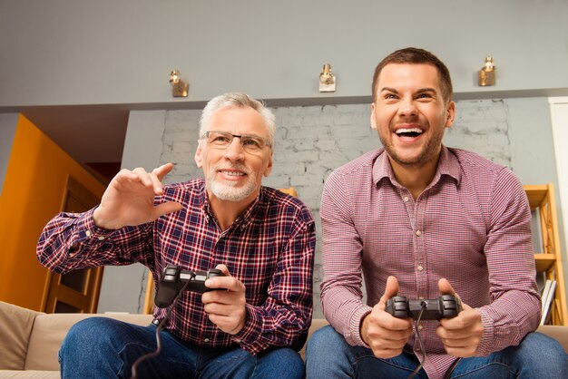 two happy friends playing video games at home