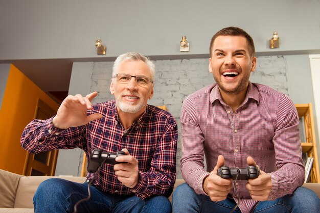 Two happy friends playing video games at home