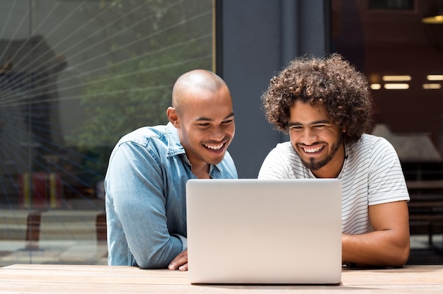 Two happy friends using laptop outdoor